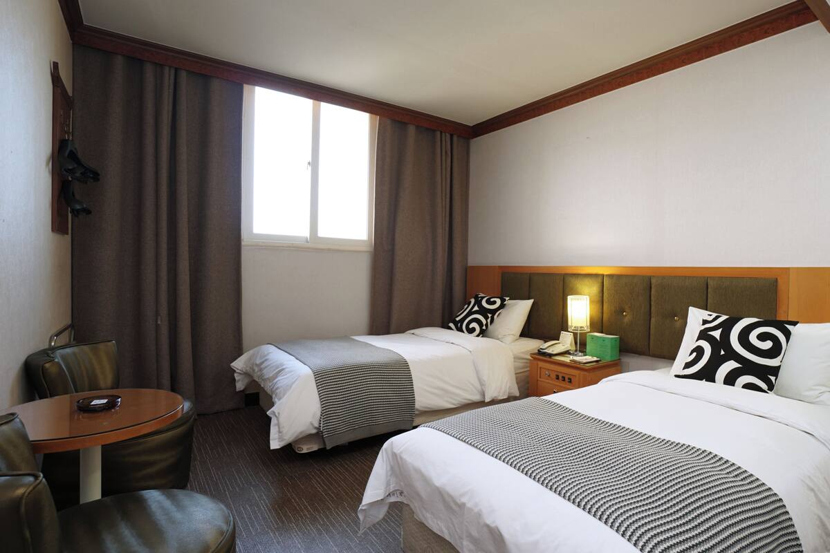 A hotel room with two beds, a desk, and a chair.