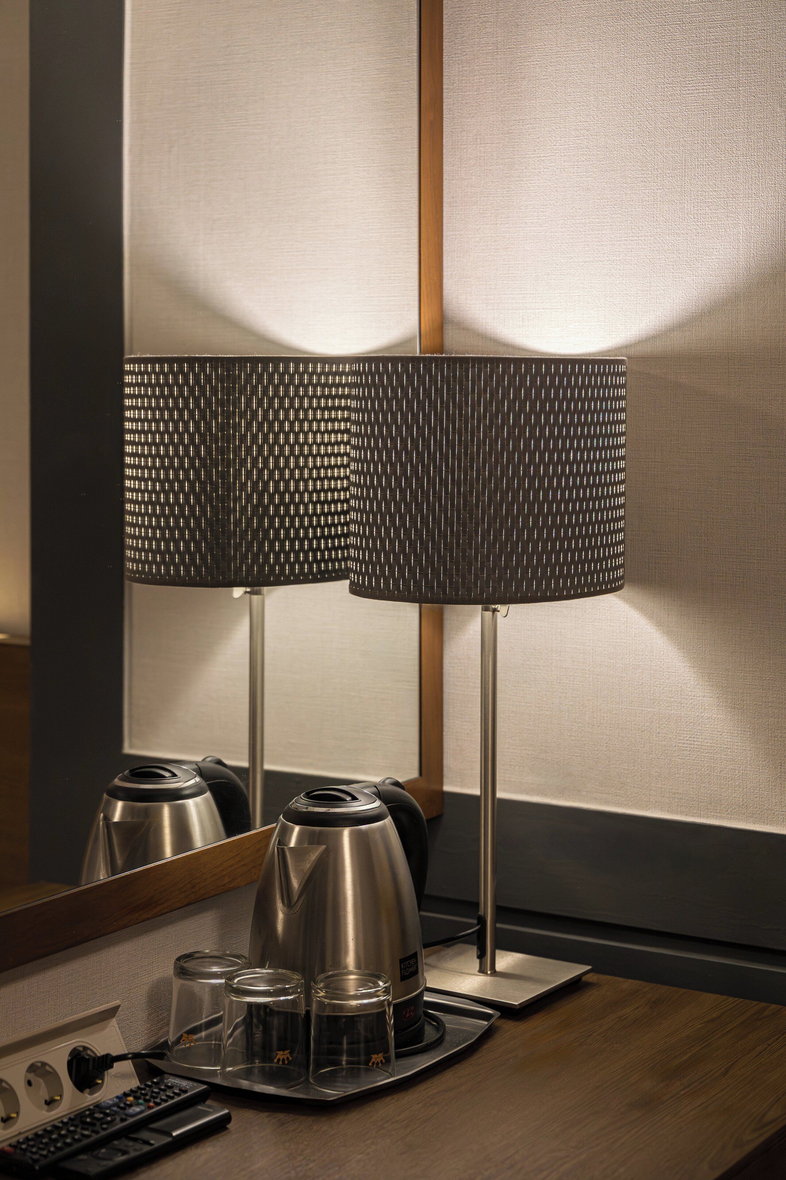 Une chambre d’hôtel moderne, dotée d’une élégante machine à café au design métallique, d’une télécommande et d’un plateau avec des verres et une tasse.
