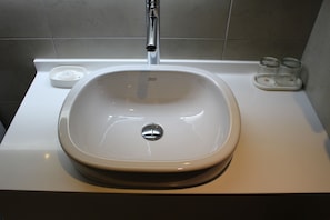 Un lavamanos de baño con un grifo moderno y un jabonera.