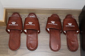 Cuatro pantuflas marrones con el logo de 'Hotel Crown'.