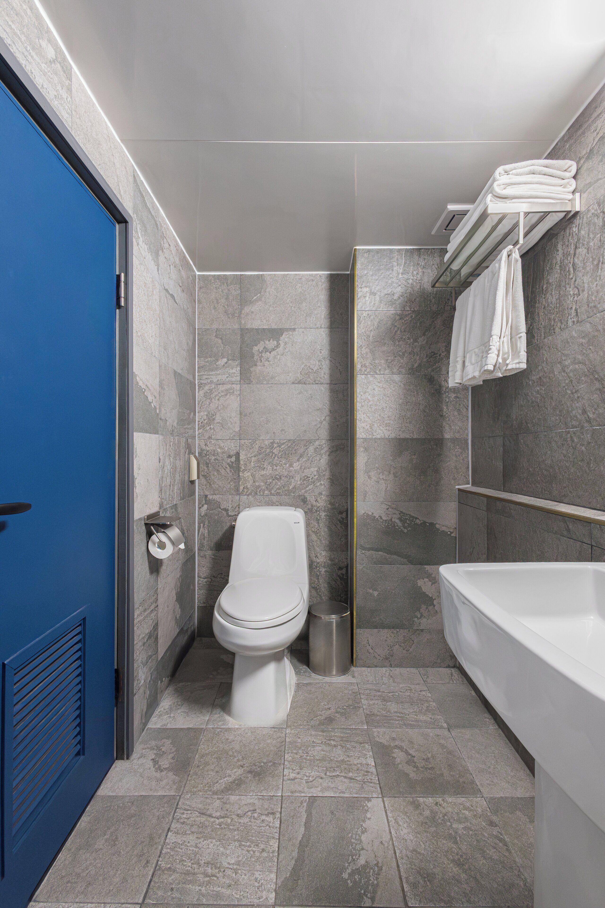 A bathroom with a toilet, a sink, and a blue door.