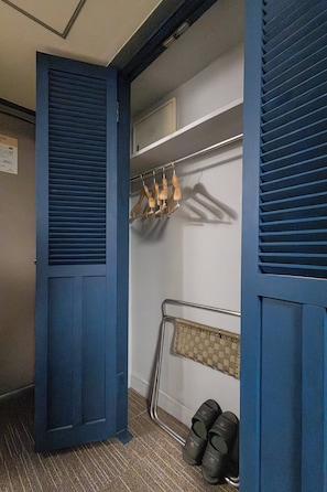A room with a blue door, a coat rack with wooden hangers, a metal rack with shoes, and a tiled floor. - Insadong Crown Hotel (Seoul)