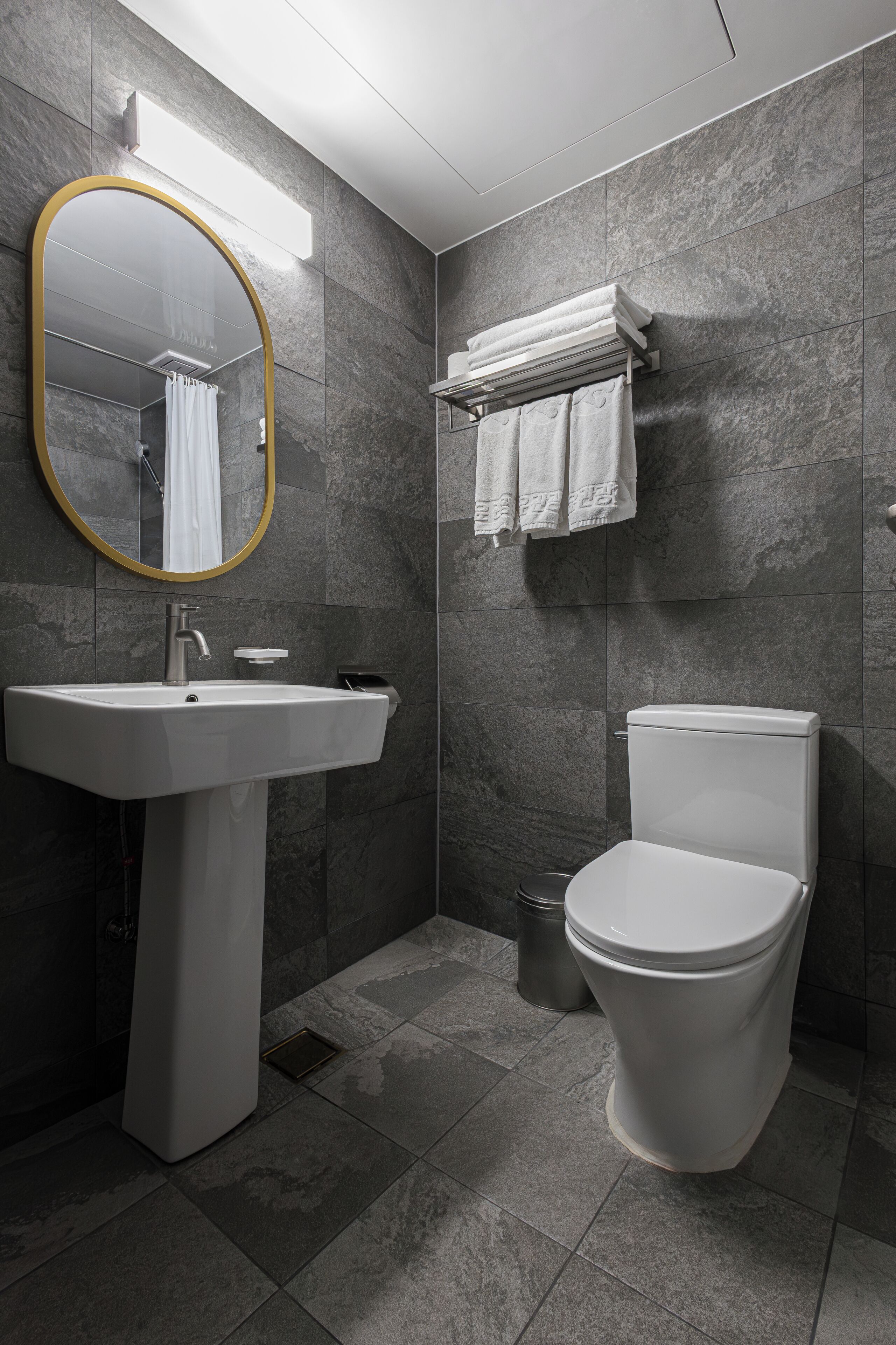 Un baño moderno con un lavamanos pedestal, un inodoro y un perchero para toallas.