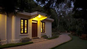 A house with a well-lit entrance, a gravel driveway, and a bench in the garden. - Hanthana Boutique Villa by Amaya (Kandy)