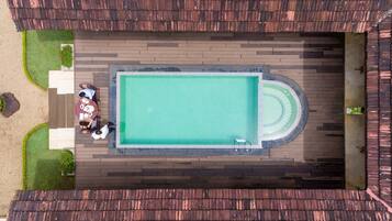 Una piscina en la azotea con un patio circundante, un espacio de descanso y un elemento decorativo de agua circular.