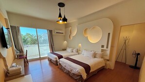 A hotel room with two beds, a desk, a chair, a TV, and a large window with a view. - Happy Life Hostel (Taitung)