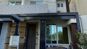 A multi-story building with a tiled facade, a gated entrance, and a small outdoor seating area. - Happy Life Hostel (Taitung)