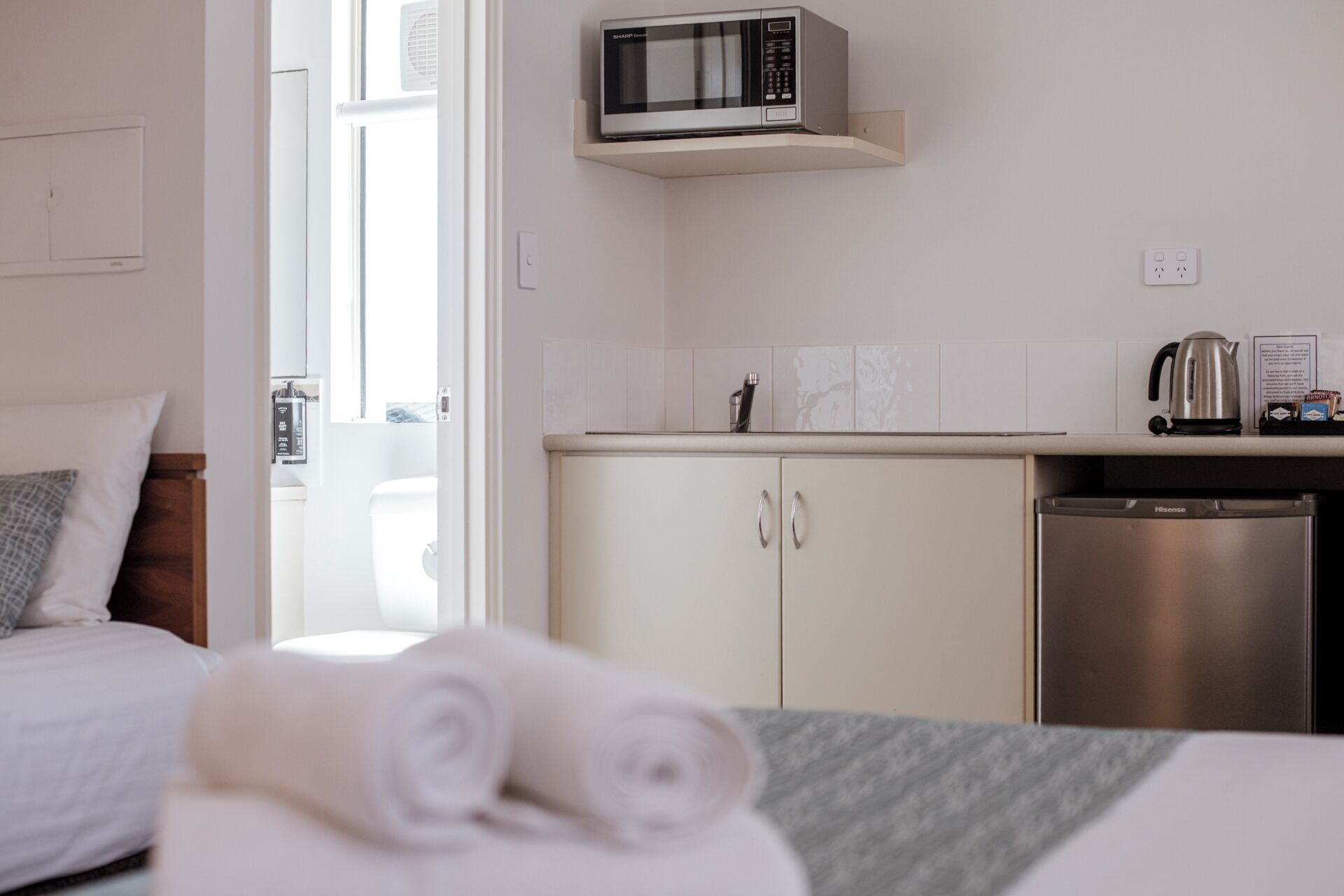 Une chambre d’hôtel moderne équipée d’un lit, d’une kitchenette avec un four à micro-ondes, une machine à café et un lave-vaisselle.