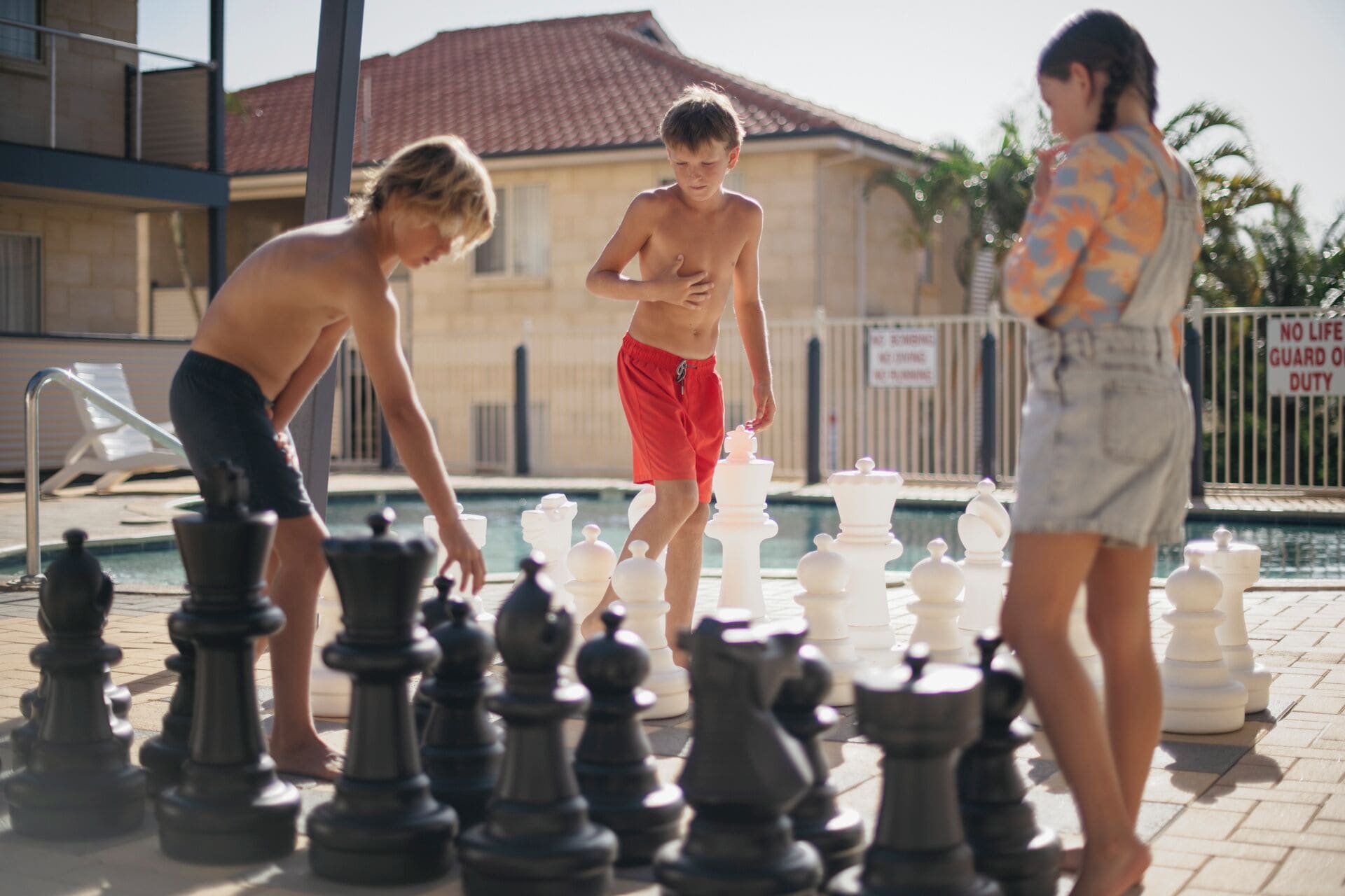 A poolside chess game with players and chess pieces.