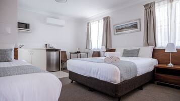 Een hotelkamer met twee bedden, een kitchenette, een bureau en uitzicht op een woestijnlandschap.