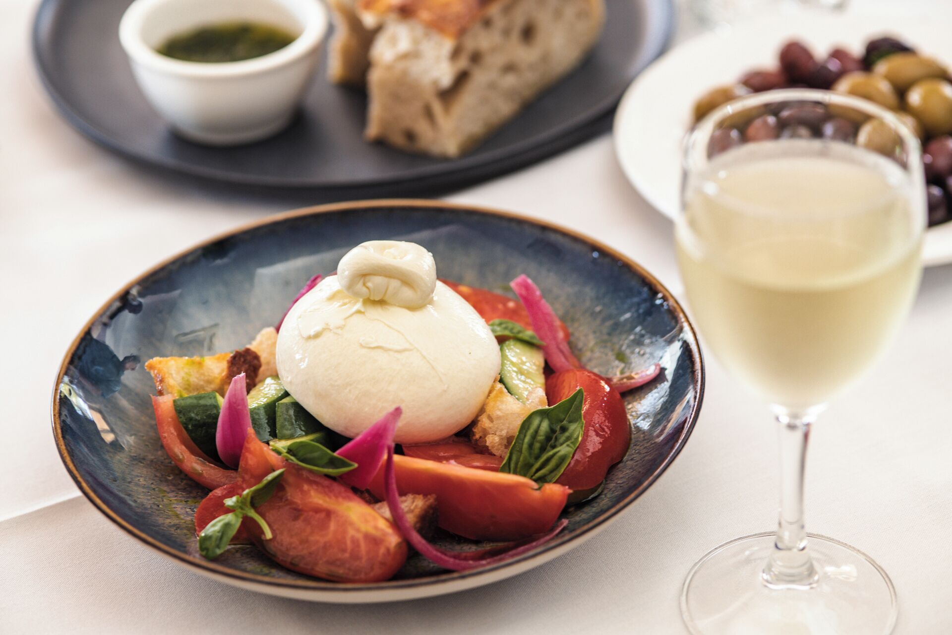 Une assiette de nourriture avec une sauce blanche, des légumes et du pain, posée sur une table.