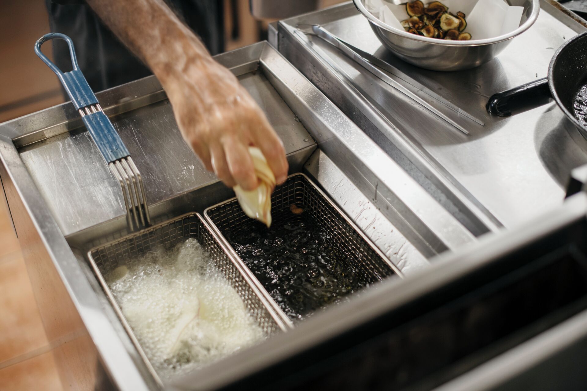 A person using a deep fryer to cook food.