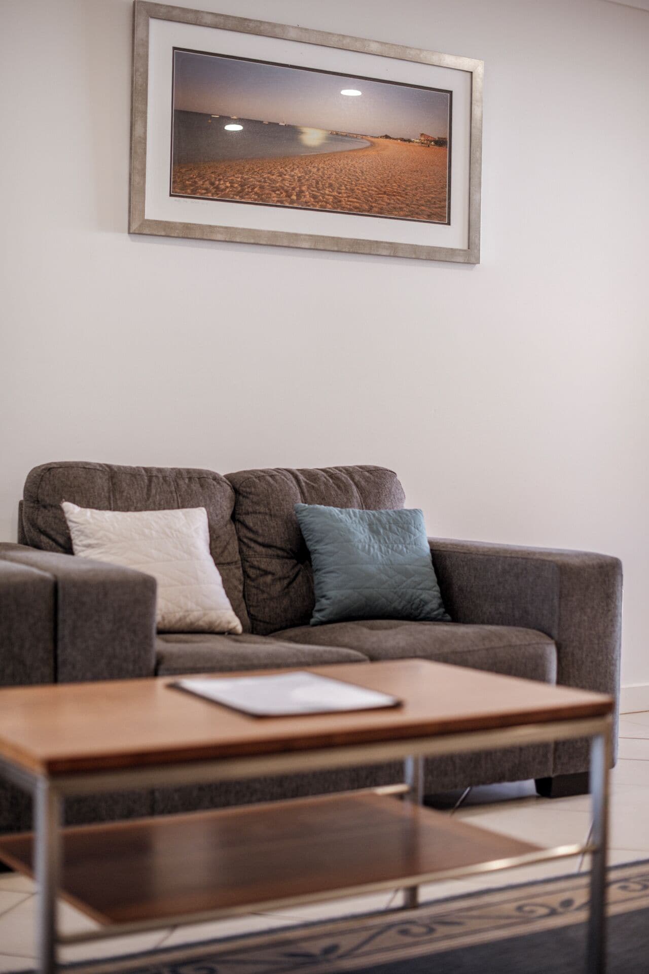 A modern living room with a grey sofa, two pillows, and a wooden coffee table.