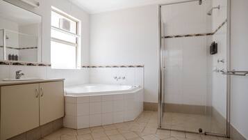 A bathroom with a bathtub, a glass shower enclosure, and a vanity with a mirror.