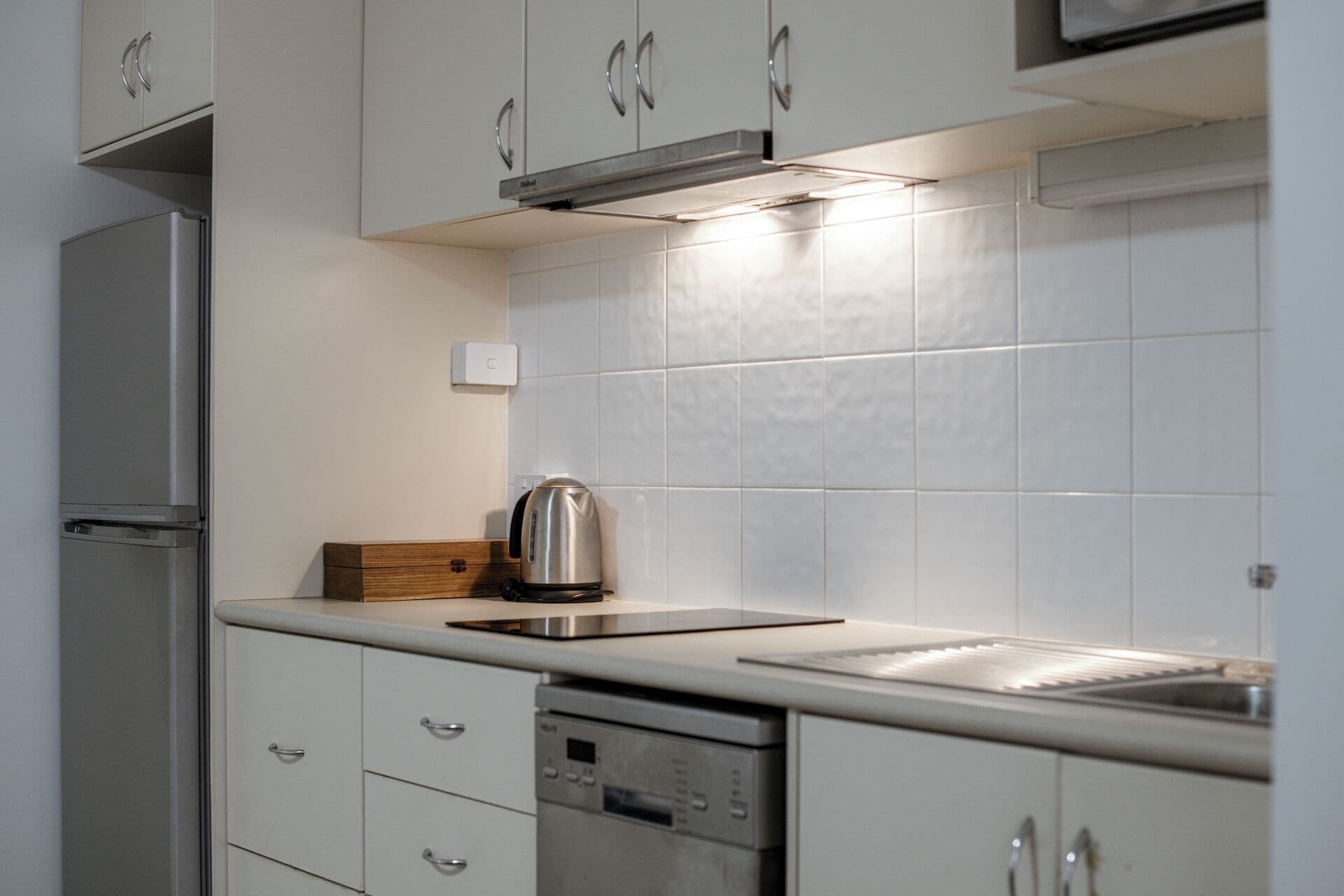 A modern kitchen with white cabinets, stainless steel appliances, and a tiled backsplash.