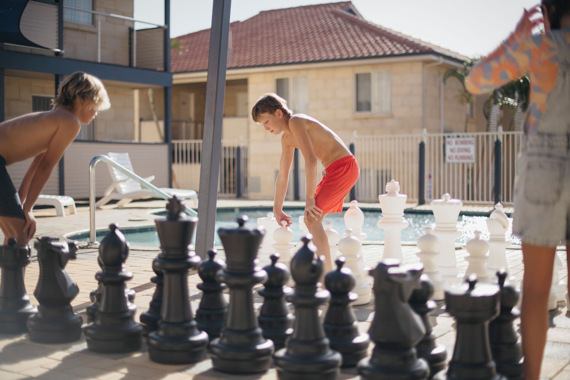 A poolside chess game with players and chess pieces.
