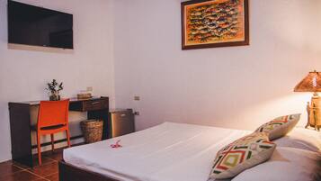 A bedroom with a bed, a desk, a chair, a television, and a wall-mounted artwork.