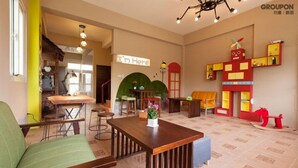 A cozy interior with a wooden table, green sofa, and a colorful play area with a red structure. - I'm Here B&B-Peng's family (Taitung)