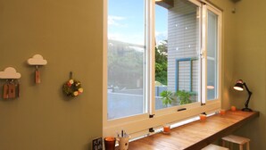 A kitchen with a wooden bar counter, stools, and a window with a view of the outside. - I'm Here B&B-Peng's family (Taitung)