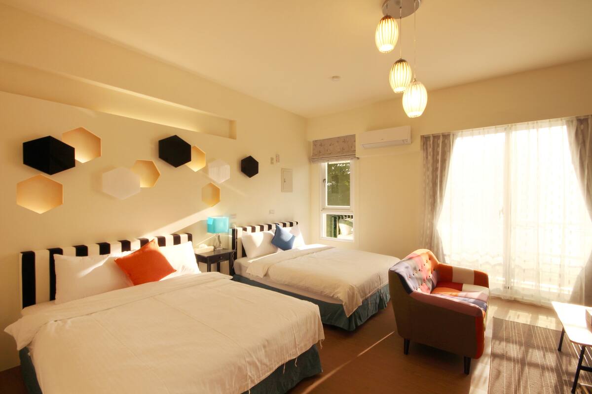 Une chambre d’hôtel avec deux lits, un canapé et une fenêtre avec des rideaux.