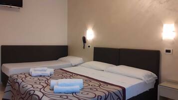 A hotel room with two single beds, a flat-screen TV mounted on the wall, and a bedside telephone.
