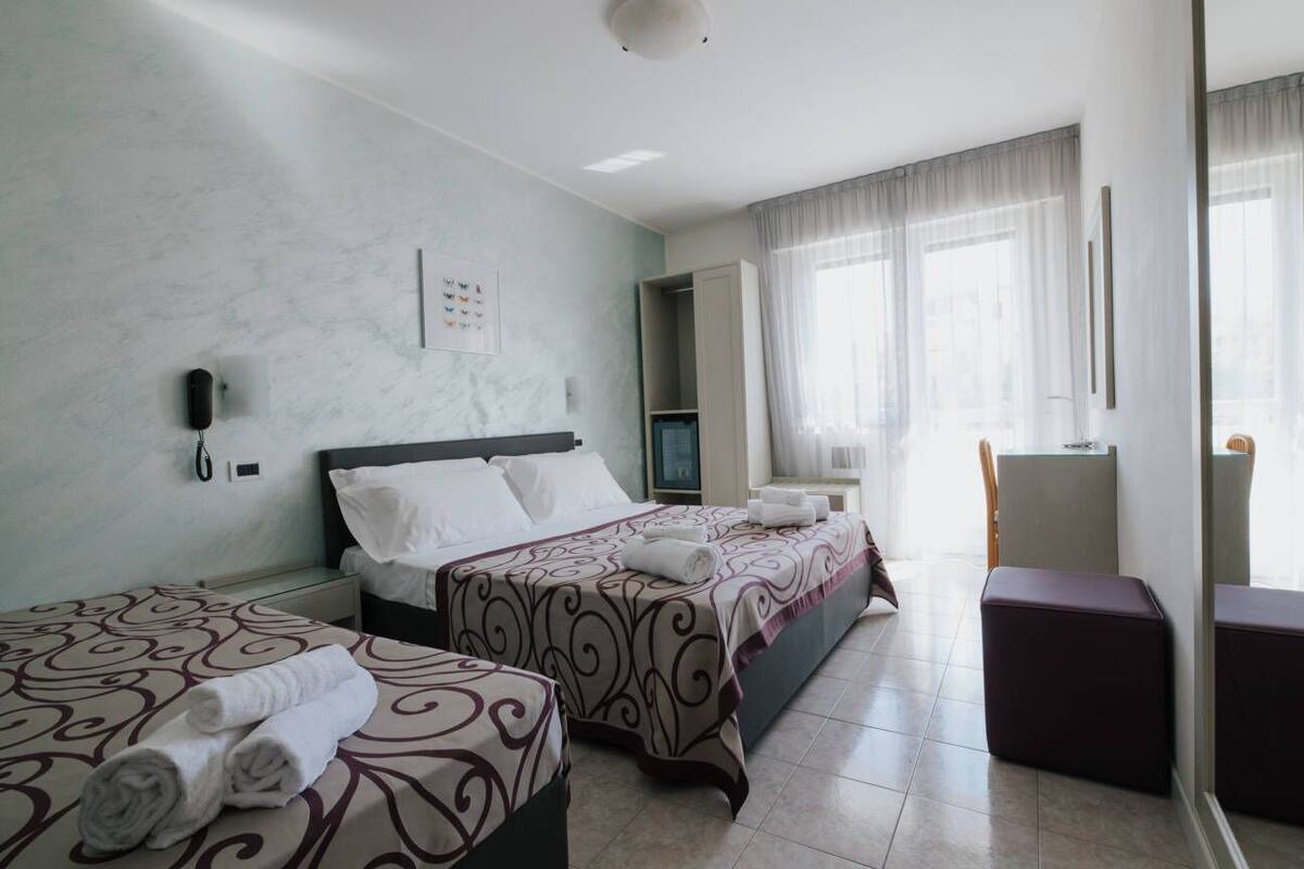 Una camera d'albergo con due letti, una televisione, una scrivania e una sedia.