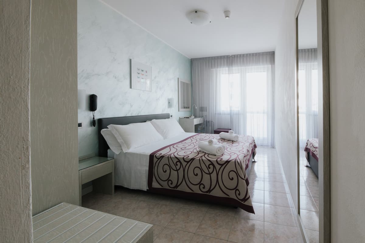 Camera d'albergo con un letto, un comodino e uno specchio grande.