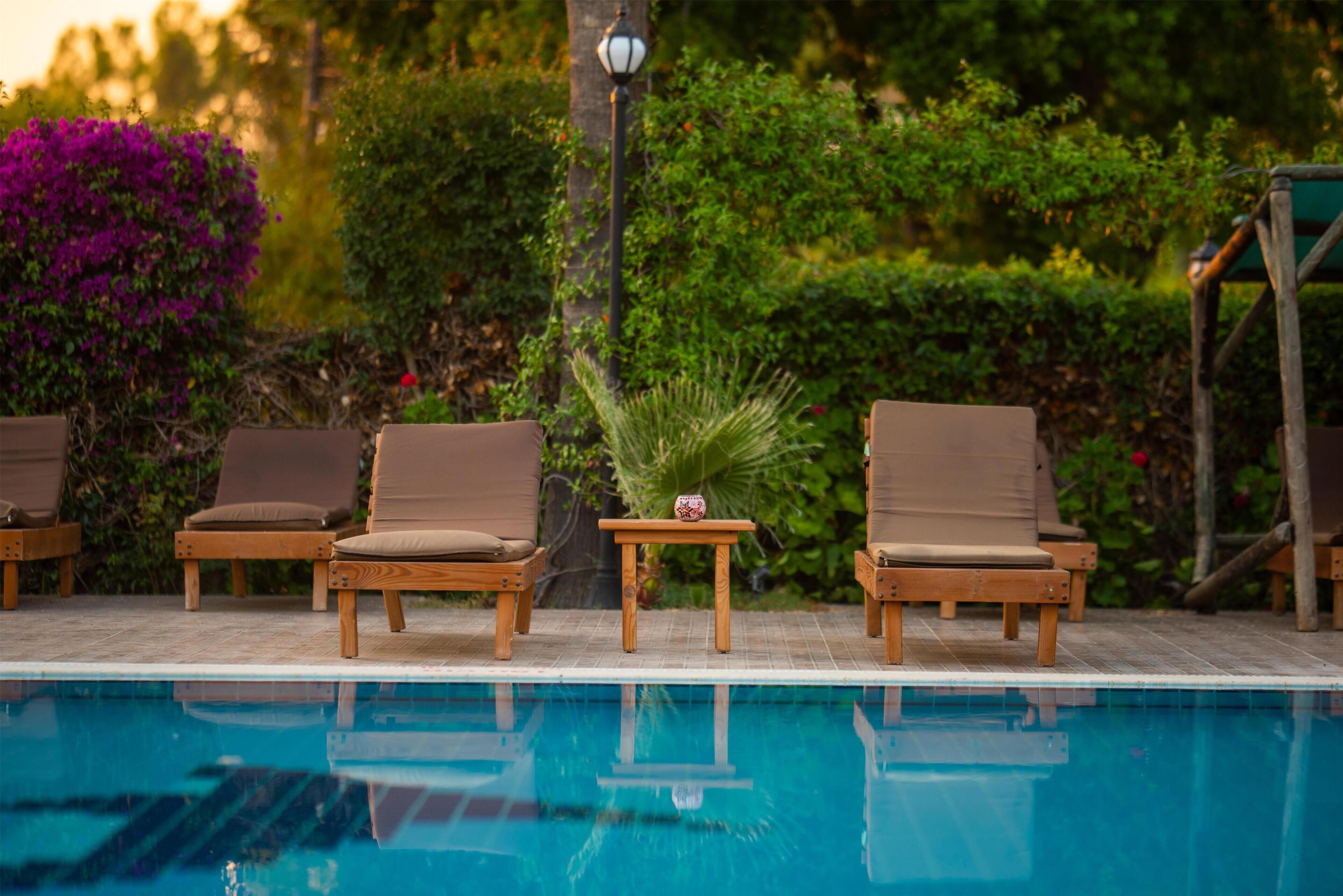A poolside area with wooden lounge chairs and a small table with a decorative item.