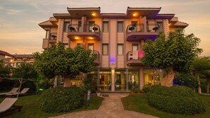 A multi-story hotel with a central entrance, balconies, and a stone pathway leading to the entrance. - Golden Moon Hotel (Fethiye)