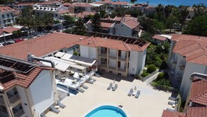 A rooftop pool area with lounge chairs and a swimming pool surrounded by buildings with red-tiled roofs. - Karbel Beach Hotel (Fethiye)