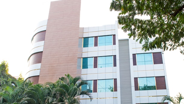 A modern hotel with a prominent 'HOTEL GALAXY' sign, featuring a mix of glass and wooden facade, and surrounded by lush greenery. - Galaxy Hotel (Mumbai)