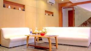 A modern lobby with a white sofa, a wooden coffee table, and decorative vases on shelves. - Galaxy Hotel (Mumbai)