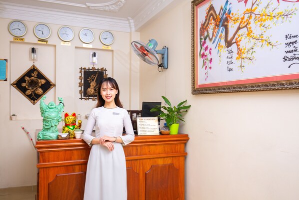 A reception desk with a clock, a framed artwork, and a sign indicating tour booking.