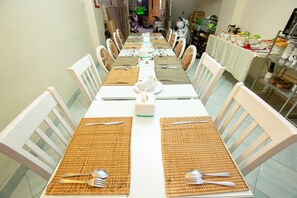 A long dining table set with white chairs, arranged for a meal.