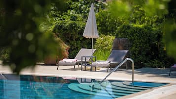 Una piscina al aire libre de temporada, sombrillas