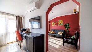 Ein modernes Wohnzimmer mit Flachbildfernseher, einer Couch, einem Essbereich mit Tisch und Stühlen sowie einer roten Akzentwand.