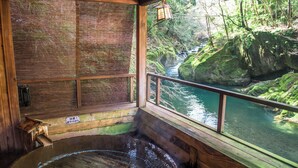 A wooden cabin with a hot tub, a view of a river, and a lantern hanging by the window. - LiVEMAX RESORT Amagi-Yugashima (Izu)