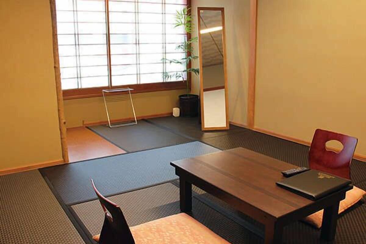 A tatami mat room with a wooden table, a red chair, and a black laptop.