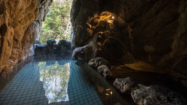 A natural hot spring with a tiled floor and rocks, surrounded by cave walls. - LiVEMAX RESORT Amagi-Yugashima (Izu)