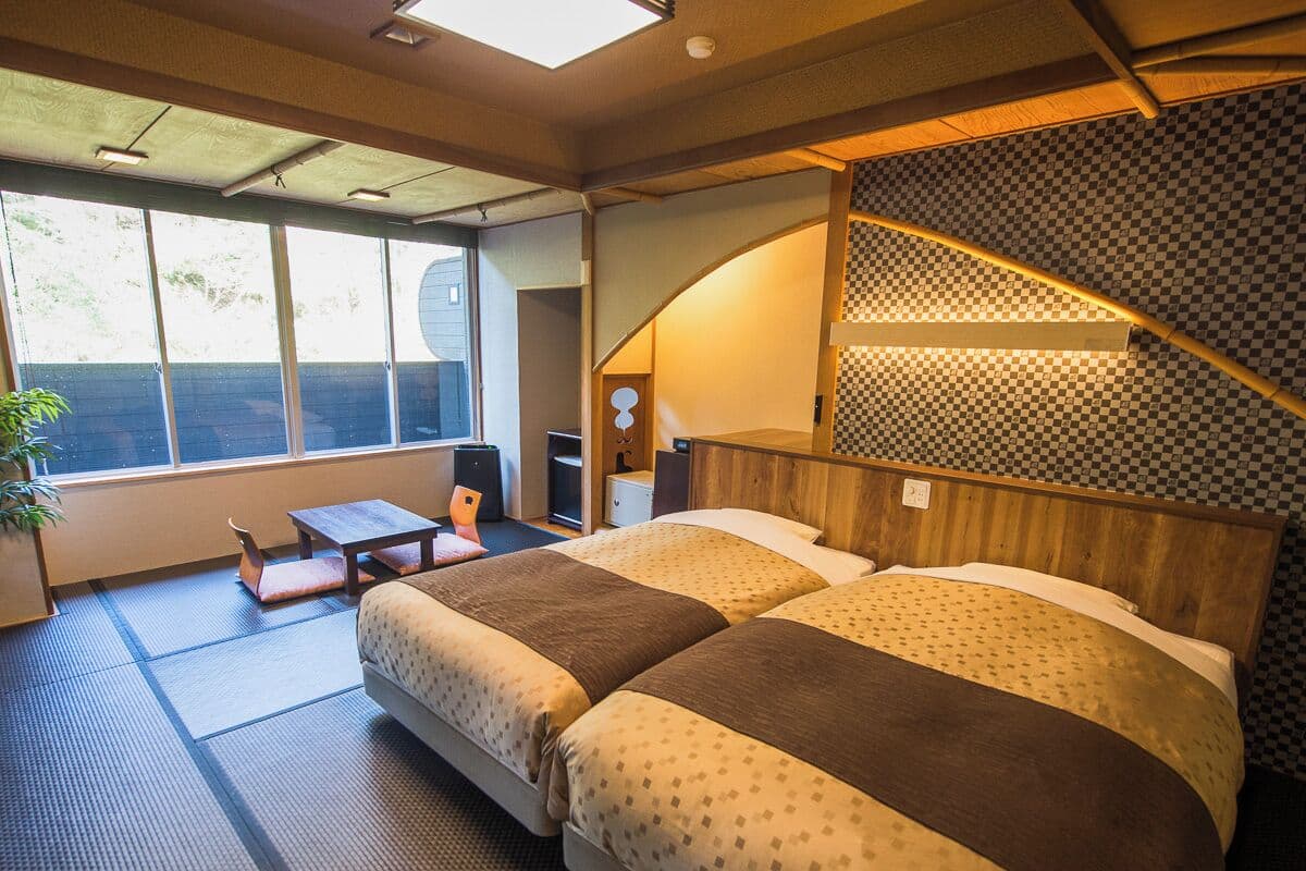 Habitación de hotel con una cama grande, una mesita y vistas al exterior por la ventana.