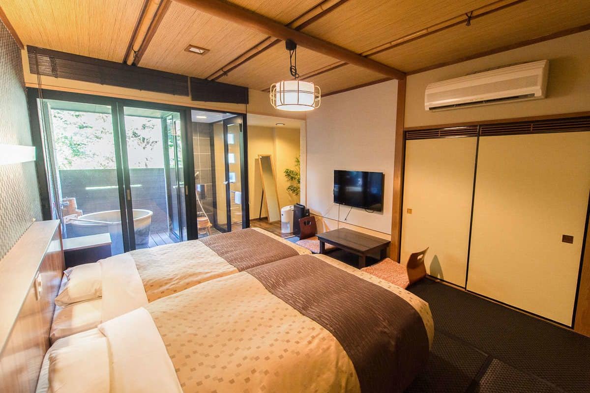 A hotel room with a large bed, a television, and a sliding glass door leading to a balcony.