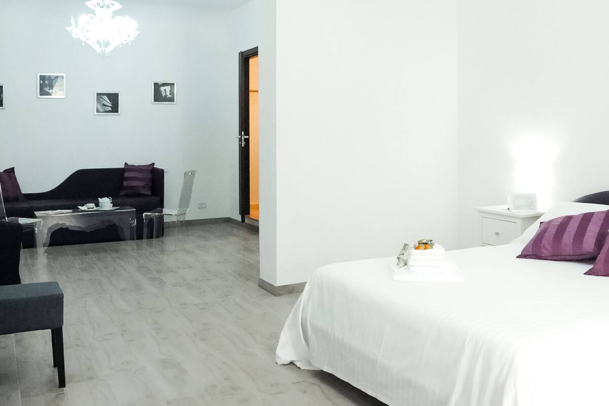 Una camera d'albergo con un letto, un divano, un tavolino e un comodino.