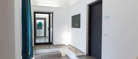 A modern hallway with a staircase, a door, and a wall-mounted light fixture.