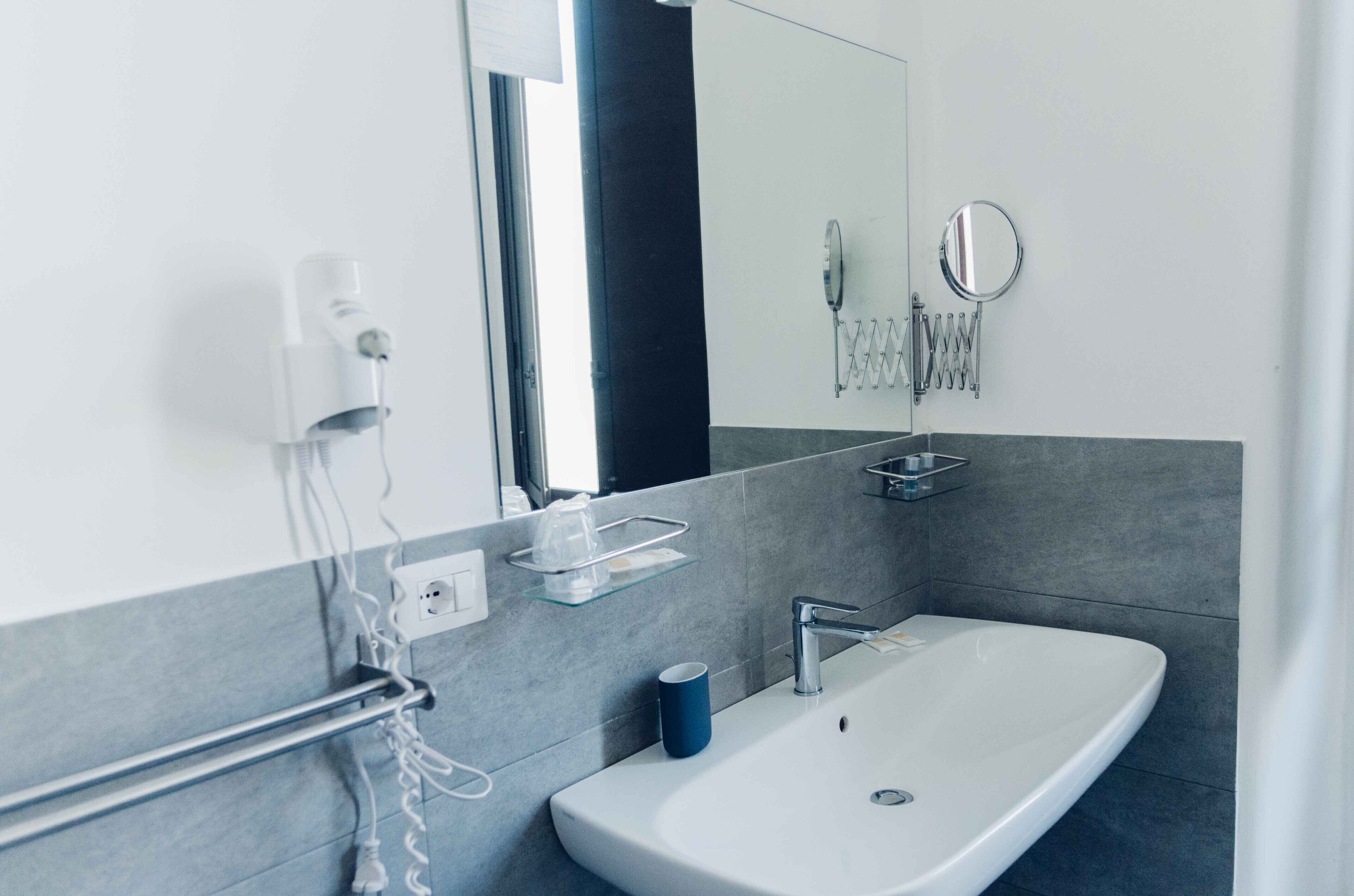 Een moderne badkamer met een witte wasbak, een spiegel en een handdoekrek.