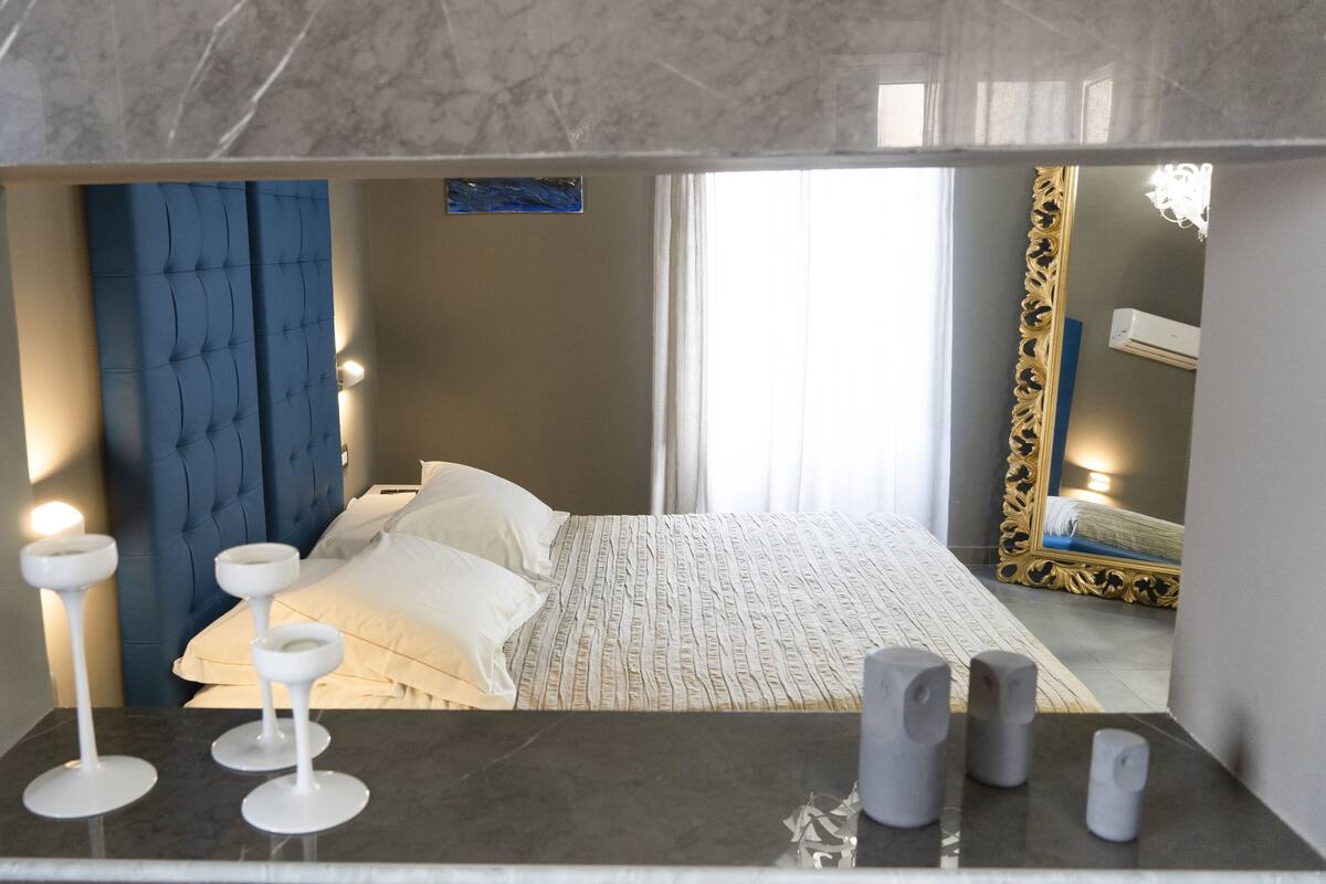 Una camera da letto moderna con un letto, lampade da comodino e uno specchio.
