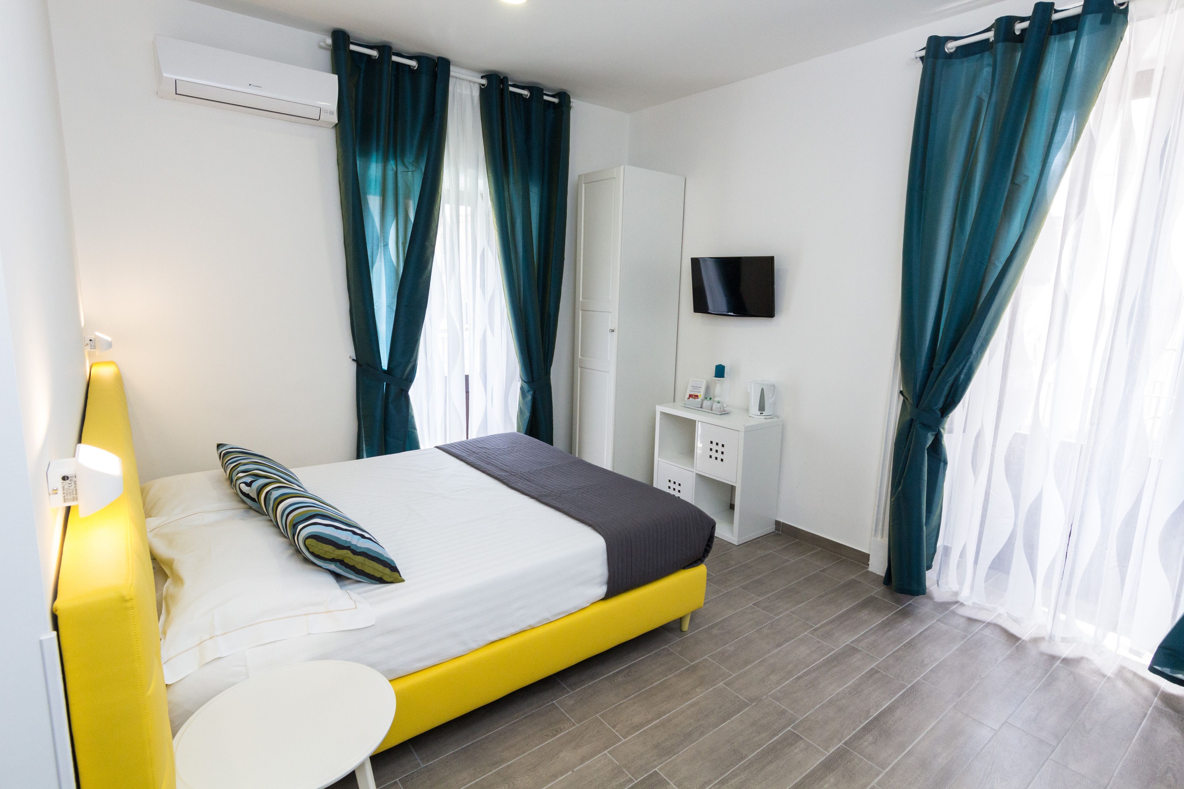 Une chambre d’hôtel moderne équipée d’un lit, d’une table de chevet, d’une télévision et d’une armoire.