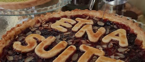 Un expositor de postres con una tarta que indica "Crostata con Mazzarella di Sbaglia e Mandorle" y otra que muestra la inscripción "ETNA SUITE".