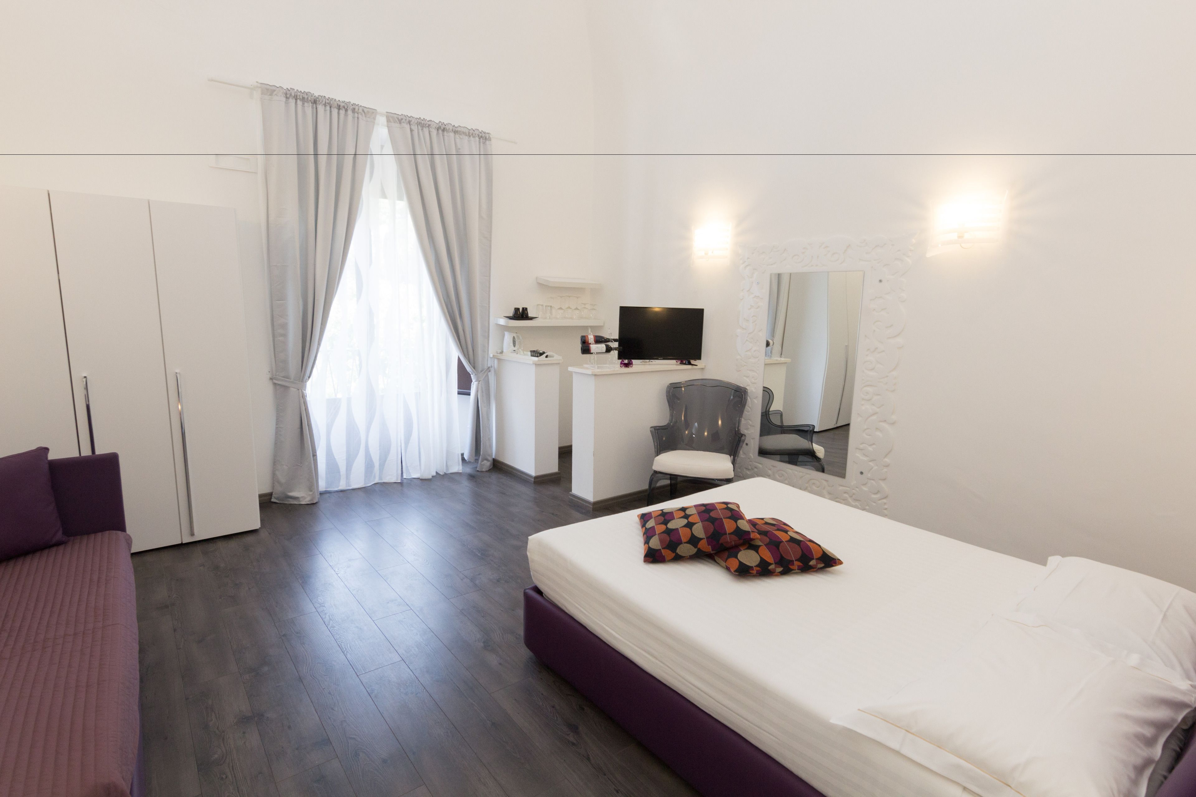 Une chambre d’hôtel moderne avec un grand lit, un bureau équipé d’un ordinateur, une chaise et une armoire.
