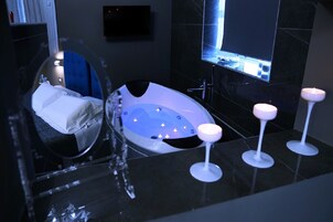 Un baño moderno con una bañera grande, un espejo y velas en la encimera.