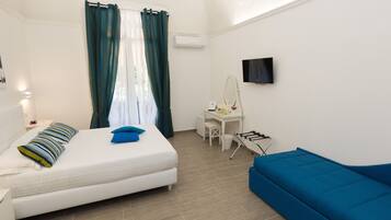Un dormitorio con cama, escritorio, silla, sofá azul y televisión.